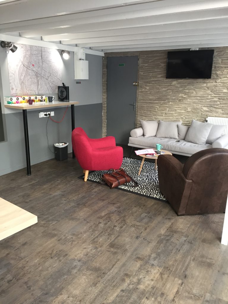 Espace d’accueil d’une agence, canapé, fauteuil rouge et sol imitation bois