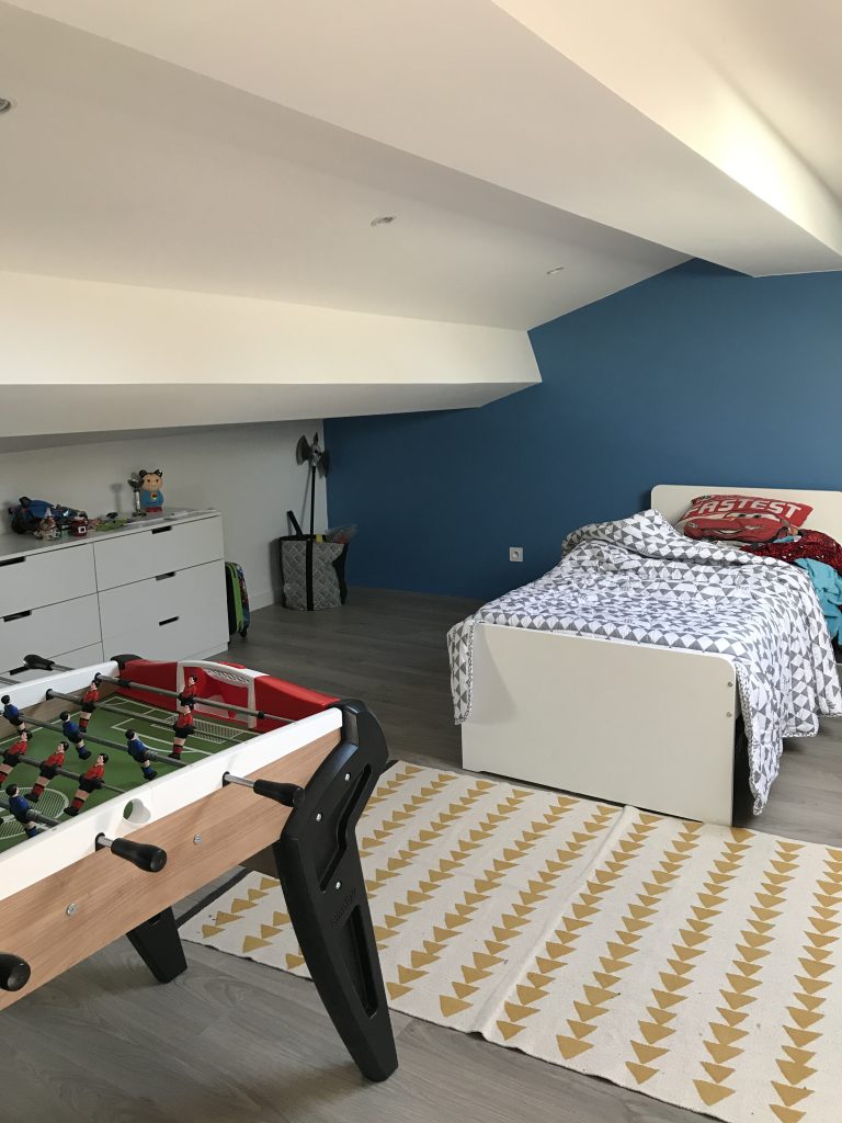 Chambre mansardée rénovée, mur bleu et sol stratifié