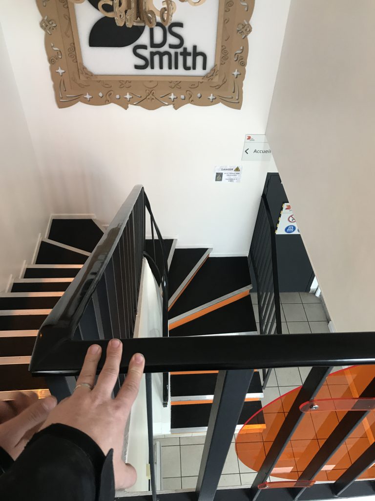Escalier d’un site d’entreprise, nez de marche orange et garde-corps noir
