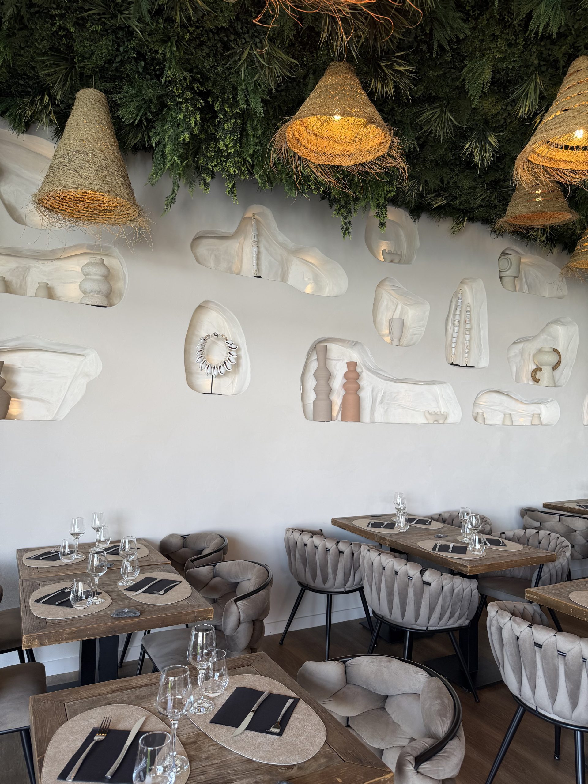 Salle du restaurant D’Calé, niches sculptées dans le mur et suspensions en fibre naturelle