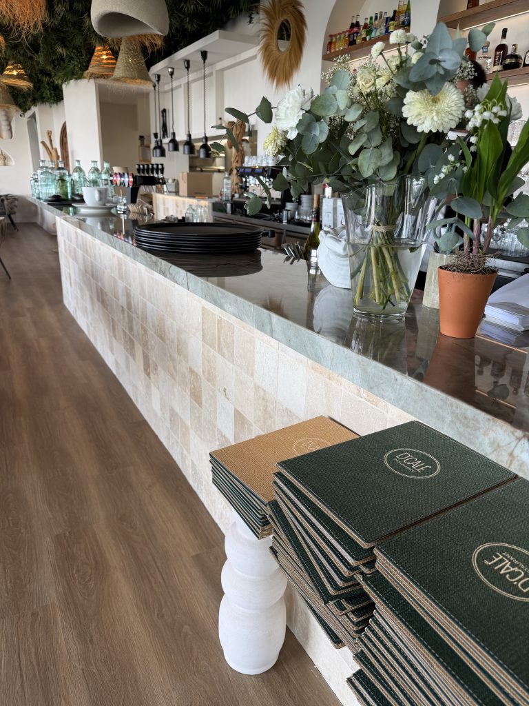 Comptoir du bar habillé de carreaux blancs, plan en pierre et bouquet de fleurs