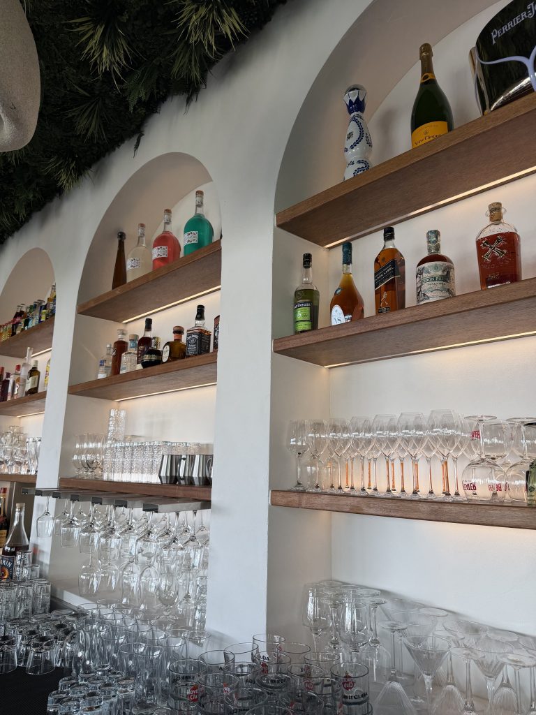 Bar du restaurant D’Calé, étagères rétroéclairées sous des arches blanches