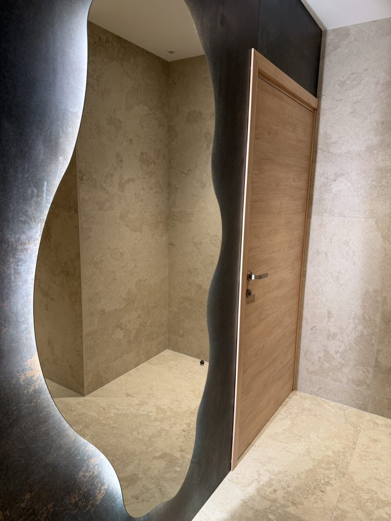 Miroir à forme organique rétroéclairé et murs à l’aspect pierre